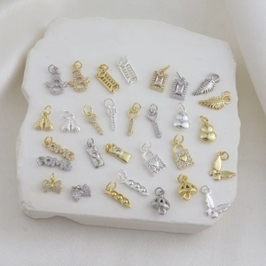 Macro view of assorted 18K gold and silver charms including key, heart, and butterfly designs