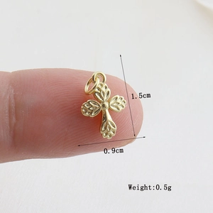 Macro shot of small gold cross charm with leaf texture measuring 1.5cm by 0.9cm