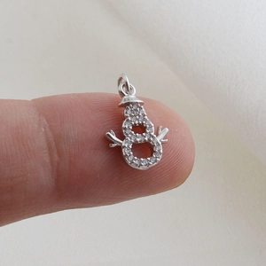 Macro shot of silver snowman charm with sparkling pavé crystals held in hand