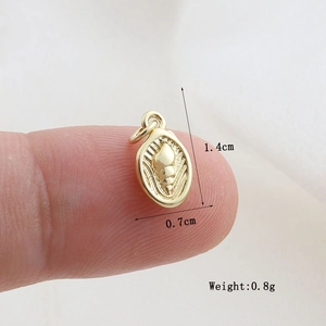 Macro detail of golden oval shell pendant with measurements showing small jewelry scale