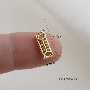 Macro shot of a mini golden abacus pendant measuring 1.7cm by 0.8cm on a fingertip