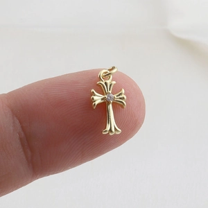Macro detail of a small vintage golden cross pendant with a central sparkling gemstone