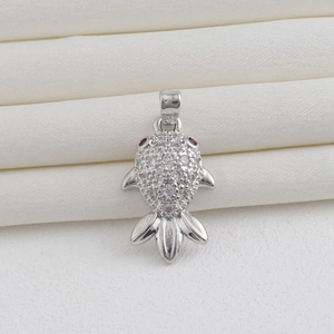 Macro shot of silver fish pendant with white zircon pavé and red gemstone eye detail