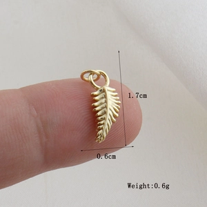 Detailed view of a gold feather pendant showing dimensions 1.7cm by 0.6cm on a finger
