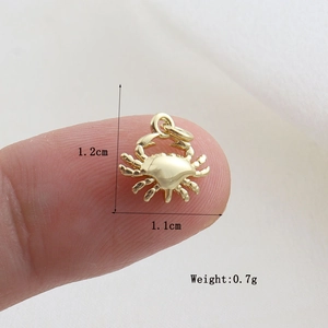 Detailed view of small gold crab charm pendant showing 1.2cm size and 0.7g weight info