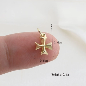 Detailed view of a gold Maltese cross pendant with dimensions 1.4cm by 0.8cm