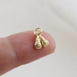 Detailed macro of tiny gold lacrosse stick pendant with fine mesh on fingertips
