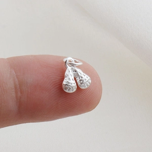 Macro shot of silver lacrosse stick pendant charm on a fingertip for size scale