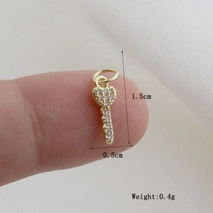 Detail shot showing heart key pendant size 1.5cm by 0.5cm on fingertip, weight 0.4g