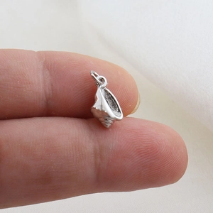 Macro shot of a tiny silver conch pendant with realistic textures for DIY jewelry making