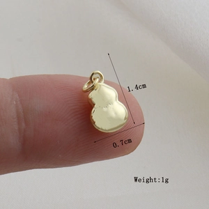 Golden gourd-shaped pendant measuring 1.4cm by 0.7cm shown for size comparison