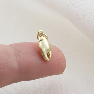 Macro view of gold crab claw pendant showing polished mirror finish on fingertips