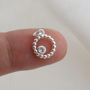 Primo piano di un piccolo ciondolo vintage in argento con zircone sulla punta del dito