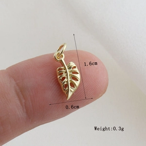 Dettaglio macro di un ciondolo foglia monstera dorata da 1,6cm con misure e peso