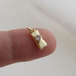 Macro shot showing the mini size of a gold-plated bow charm with a round zircon stone