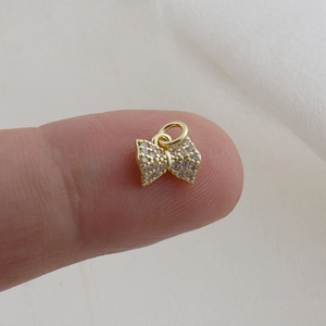 Macro shot of a tiny gold bow pendant with sparkling cubic zirconia for DIY jewelry