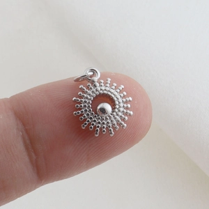 Macro di un ciondolo traforato in argento con perla centrale sulla punta del dito