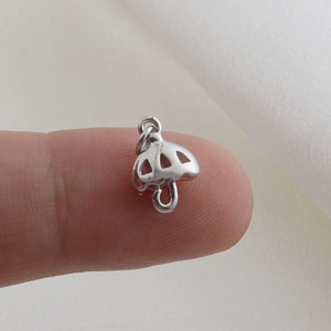 Detail of silver umbrella pendant with hollow design held on fingertip for size