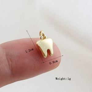Macro shot of gold tooth pendant showing size 1.2cm by 0.8cm on fingertip