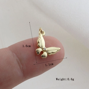 Macro detail of a 1.6cm golden butterfly pendant with purple zircon and dimensions
