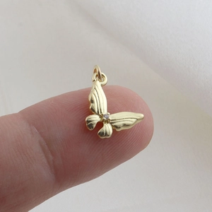 Detailed close-up of a small gold butterfly charm with brushed texture and zircon inlay