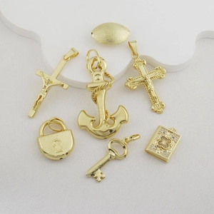 Detailed view of gold plated metal pendants featuring cross, anchor, lock and key shapes