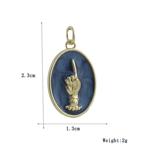 Detail view of oval gold-plated pendant with blue marble inlay and hand relief, 2.3cm height