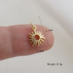 Macro di un piccolo ciondolo a forma di sole dorato sul polpastrello che ne mostra le dimensioni