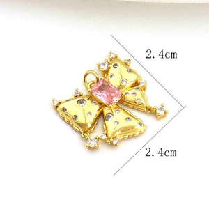 Detailed view of golden butterfly pendant with pink gemstone and zircon settings