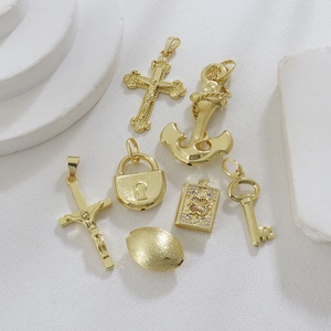 Macro view of gold plated brass charms featuring cross, anchor and locket on stone
