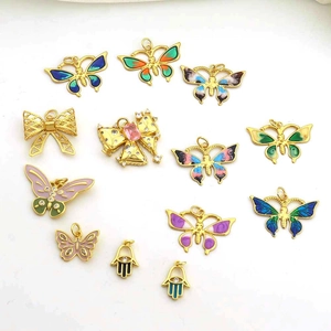 Macro shot of colorful enamel butterfly and gold-plated Hamsa pendants for DIY jewelry