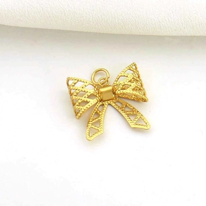 Macro detail of a golden hollow bow-knot pendant with intricate filigree texture