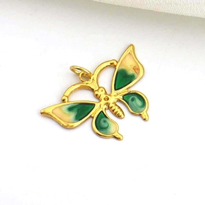 Detailed macro shot of a gold butterfly pendant with green and cream enamel finish