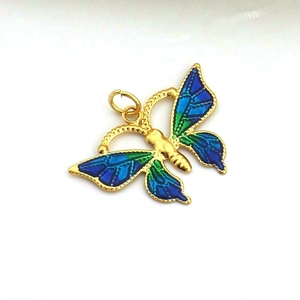 Macro detail of butterfly pendant with gold frame and blue-green enamel butterfly wings