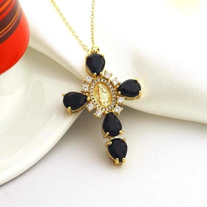 Close-up of a gold cross necklace with black teardrop stones and Virgin Mary medallion