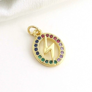 Macro detail of gold-plated lightning bolt pendant with colorful zircon stones on silk