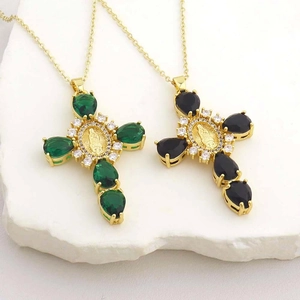 Detail of luxury cross pendant necklaces with drop-shaped emerald and black gems