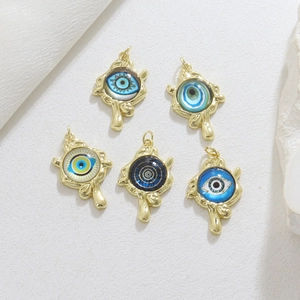 Detail shot of assorted 18K gold plated evil eye pendants on elegant silk backdrop