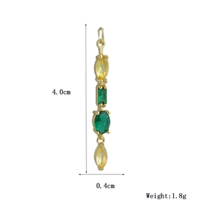 Dettaglio di un lungo ciondolo d'oro con gemme marquise gialle e pietre verdi rettangolari