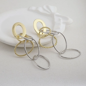 Boucles d'oreilles pendantes ovales bicolores dorées et argentées sur plateau blanc
