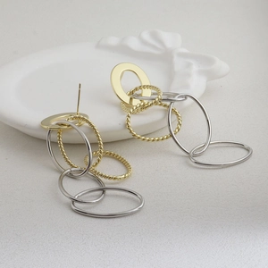 Gros plan de boucles d'oreilles entrelacées or et argent sur une assiette en céramique