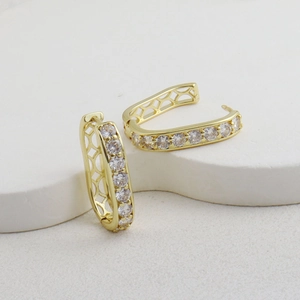 Détail de boucles d'oreilles en U dorées avec zircons et motif de maille géométrique ajouré