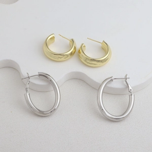 Gros plan de boucles d'oreilles créoles dorées et argentées sur un support blanc