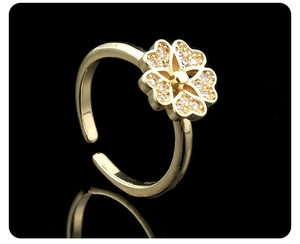 Macro shot of gold-plated flower ring with white zircon stones on a black reflective base