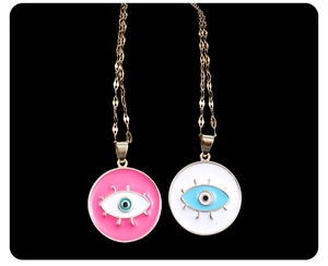 Detail of evil eye pendant necklaces in pink and white enamel with gold wavy chains