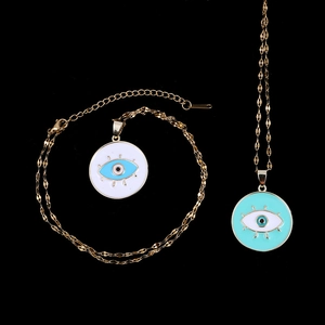Golden evil eye jewelry set featuring a pendant necklace and bracelet on black background