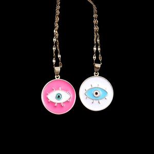 Pink and white evil eye pendant necklaces with gold chain displayed on black background