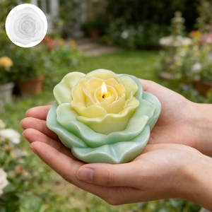 Blooming rose flower candle in gradient green and yellow shown lit in a garden setting
