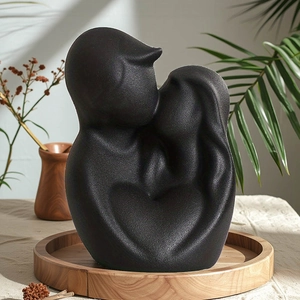 Abstract matte black ceramic couple statue forming a heart silhouette on wooden tray