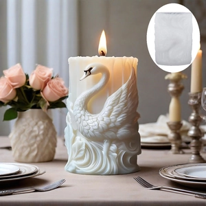 Elegant swan relief cylindrical scented candle with lit flame and floral table setting